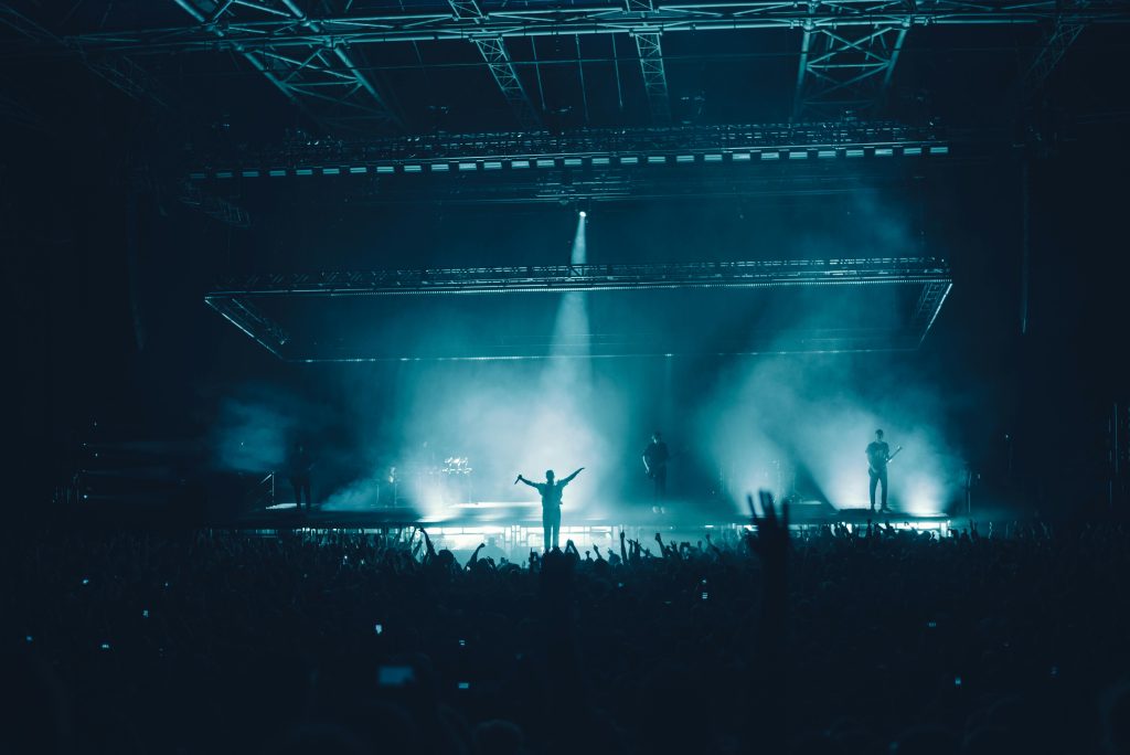 Energetic concert scene with a silhouetted performer and vibrant audience lighting.